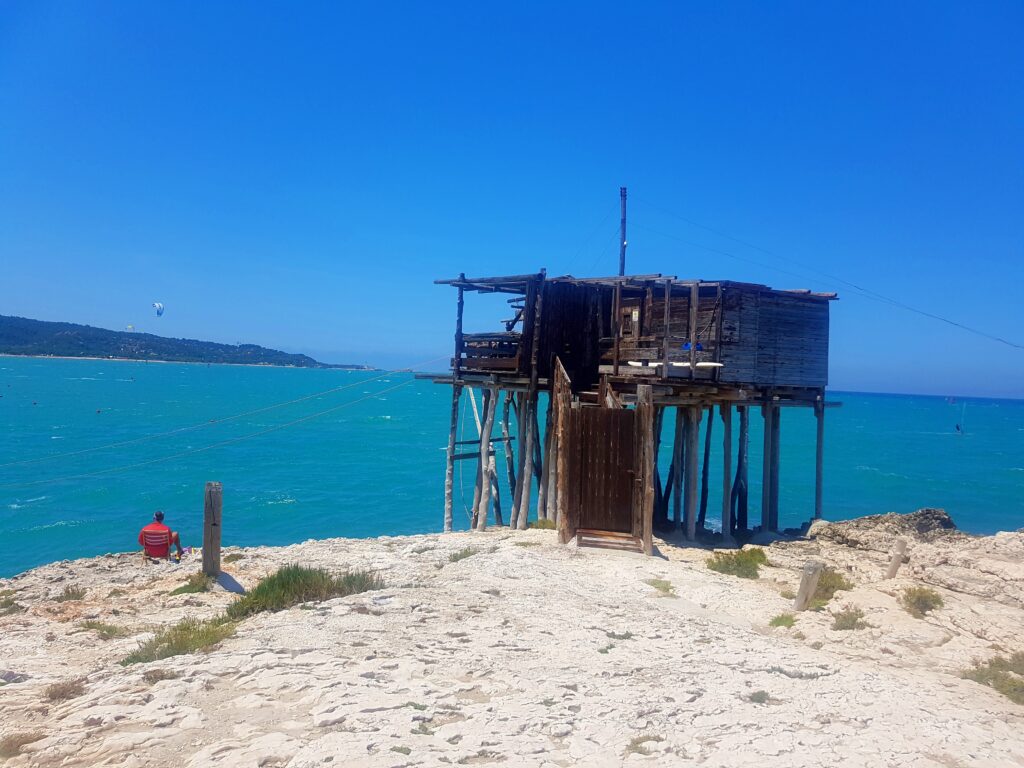 Traditional wooden fishing platform, trabucco, built on a rocky cliff over turquoise sea under a clear blue sky, Vieste, Gargano, Puglia.
