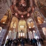 People look at the tall columns decorated with mosaics. inside the church