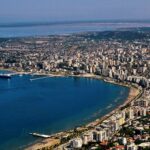 In the sea bay you can see from above a rather large city with whitish buildings, there are several high blocks of flats