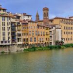 over the river with greenish water stand four-story blocks in different colors, next to them stands a church tower