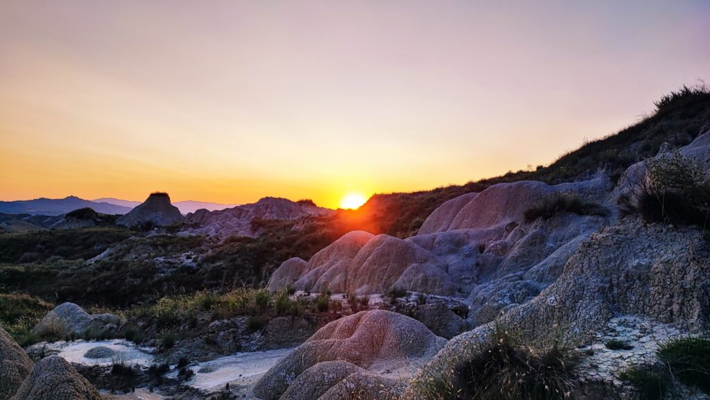 Deeply eroded clay ridges and sun-scorched valleys of the Calanchi di Pisticci badlands in Basilicata.