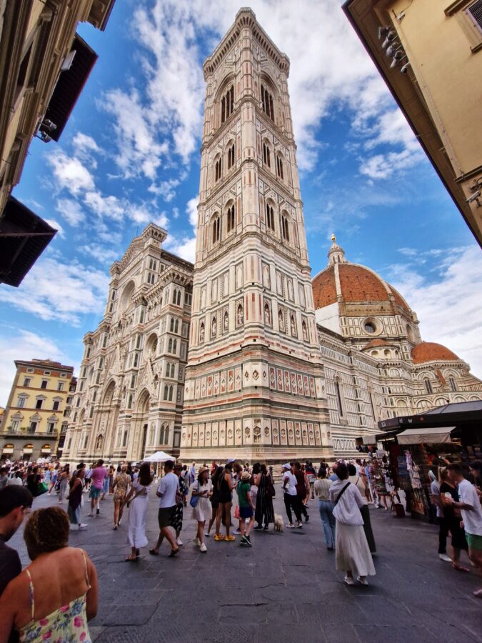 Widok na katedrę Santa Maria del Fiore i dzwónnicę Giotta we Florencji z tłumem ludzi na placu