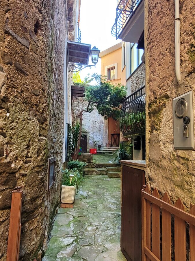 Narrow stone alley with potted plants and traditional buildings in the historic borgo of Agropoli, Campania