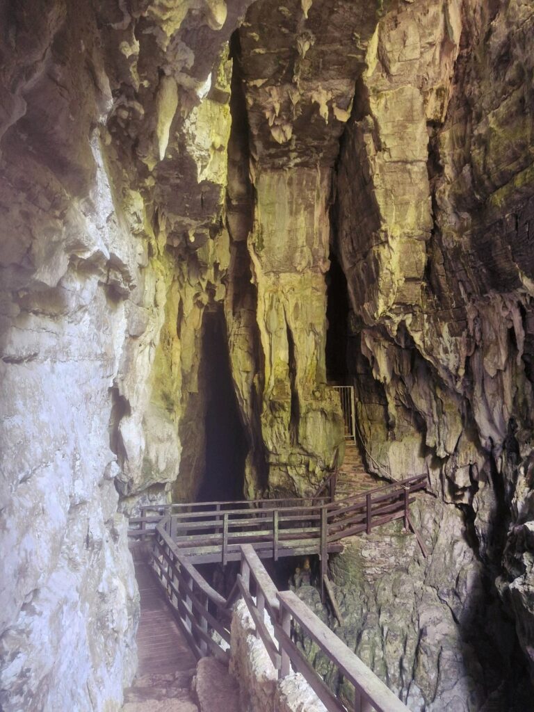 A wooden bridge runs along the rock wall in the cave.