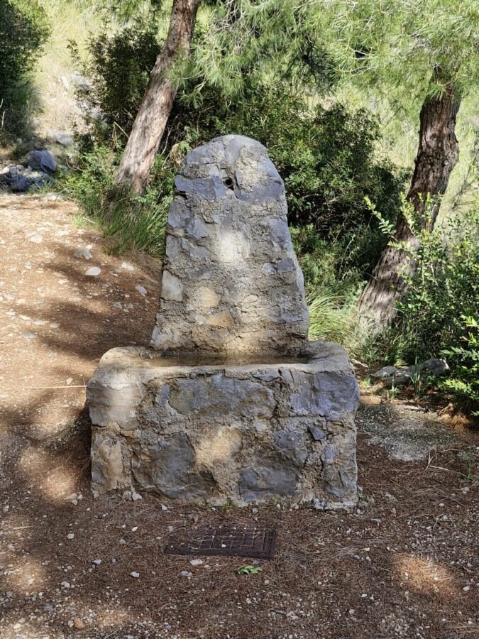 Broken stone water fountain along the dirt path of Sentiero Apprezzami l'Asino in Sapri, Campania, Italy.