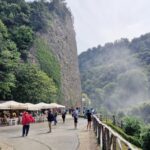 Visitors walking along the panoramic path near Marmore Falls with mist rising from the waterfall in Umbria, Italy.