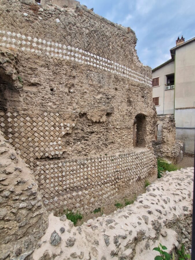 Ruins of the Roman amphitheatre in Terni Umbria, showing opus reticulatum masonry with diamond-shaped stones and arched openings.