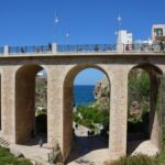 View through the stone arch of Ponte Borbonico in Polignano a Mare, Puglia, showing crowds and boats gathered for the Red Bull Cliff Diving event