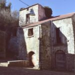 Old stone house in an Italian village with wooden shutters and weathered walls, photographed on a sunny winter day