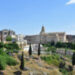 Panoramic view of the countryside around Gravina di Puglia, Italy, with ancient stone ruins on the hillside and rolling green fields in the distance