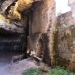 Interior of an ancient cave church in Gravina di Puglia, Italy, with stone walls, arched niches, and natural rock ceiling
