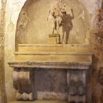 Stone altar with weathered statue of Saint Michael inside an ancient cave church in Gravina di Puglia, Italy.