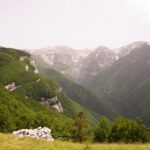 Panoramic view of Majella mountains in Abruzzo with green valleys, rocky peaks, and patches of snow to Eremo San Giovanni all'Orfento