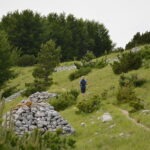 Hiker walking on a mountain trail in Majella National Park with stone cairn and green forest in Abruzzo