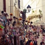 Colorful handmade crafts, dreamcatchers, and souvenirs hanging in a narrow street market of Polignano a Mare, Puglia.