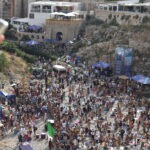 Crowded Lama Monachile beach with paddleboards and kayaks during the Red Bull Cliff Diving World Series in Puglia