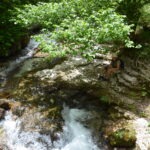 Kobieta odpoczywa nad górskim potokiem w dolinie Valle dell’Orfento w Parku Narodowym Majella – malownicze miejsce z krystalicznie czystą wodą i bujną zielenią w Abruzji.