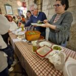 Family serving plates of homemade orecchiette with cime di rapa at a food stall during Calici nel Borgo Antico in Bisceglie’s old town.