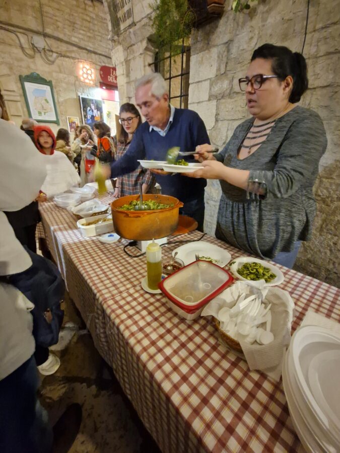Family serving plates of homemade orecchiette with cime di rapa at a food stall during Calici nel Borgo Antico in Bisceglie’s old town.