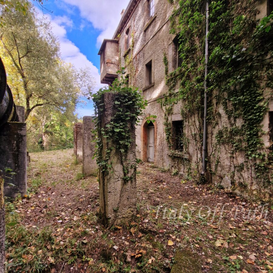 Abandoned ivy-covered house near Fara San Martino in Abruzzo, Italy, surrounded by trees and overgrown courtyard.