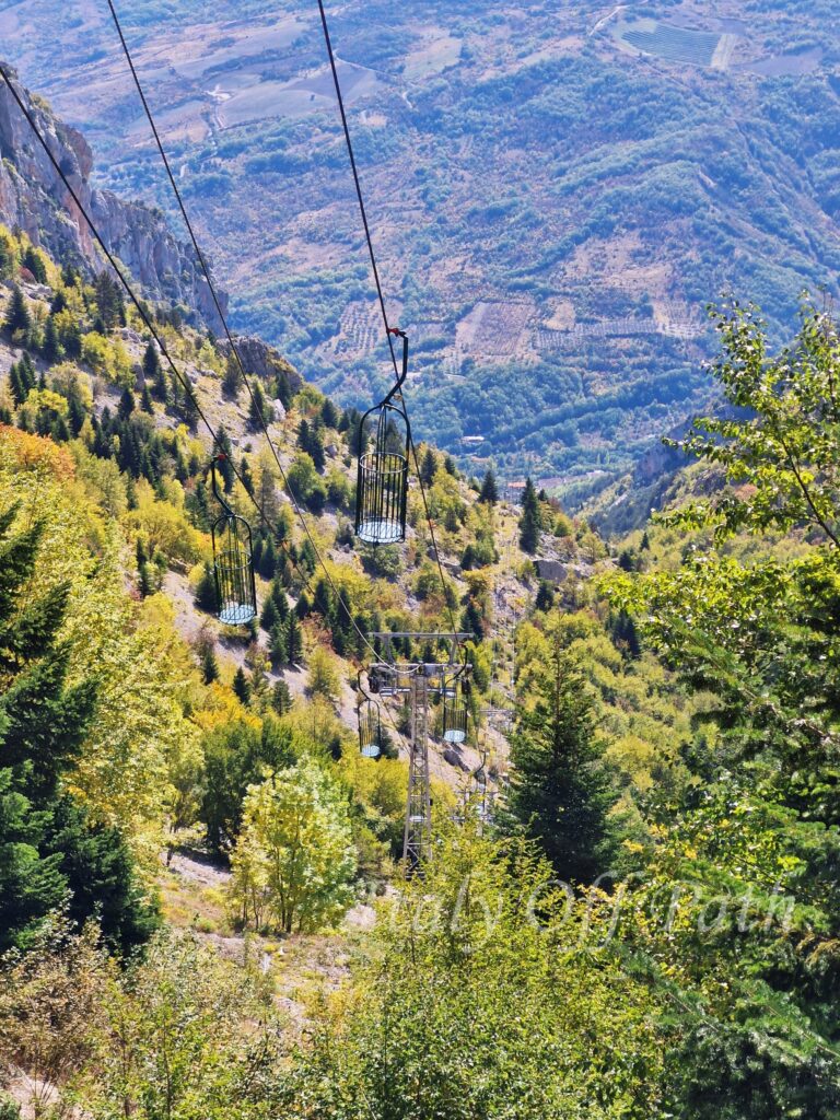 Zabytkowa kolejka linowa prowadząca do jaskini Grotta del Cavallone w Abruzji, z widokiem na górskie stoki i dolinę Majella poza utartym szlakiem w Abruzji