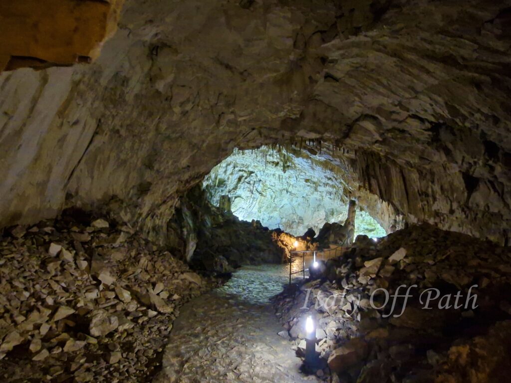 Wnętrze jaskini Grotta del Cavallone w Abruzji, oświetlona ścieżka prowadząca wśród stalaktytów i skalnych formacji.