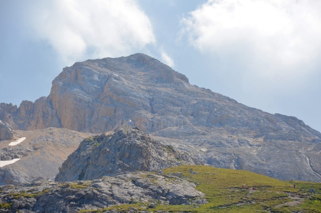 Rifugio Franchetti with an Italian flag perched on a rocky outcrop below the massive limestone slopes of the Gran Sasso massif, Abruzzo, Italy.