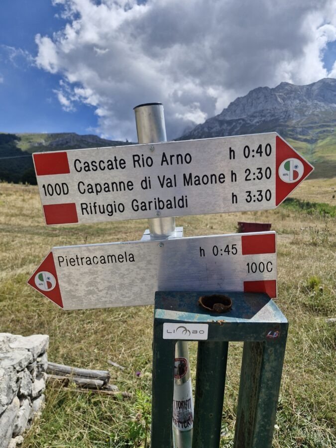 Hiking trail signpost marking path 100D to Cascate Rio Arno and 100C to Pietracamela in Abruzzo, Italy