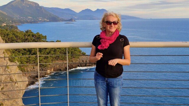 Woman standing on the glass floor of the cliffside skywalk viewing platform above the sea in Maratea, Basilicata.