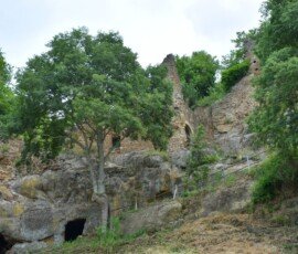 Narrow path and stone ruins built into rocky cliffs in the ghost town of Antica Monterano, Lazio, Italy.