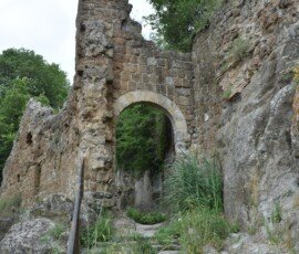Stone stairs leading through an arched ruin gateway in the ghost town of Antica Monterano, Lazio, Italy.