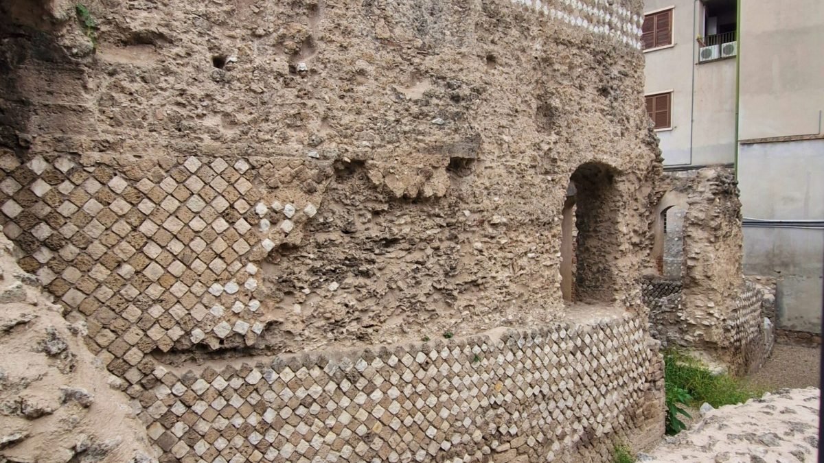 Ruins of the Roman amphitheatre in Terni Umbria, showing opus reticulatum masonry with diamond-shaped stones and arched openings.